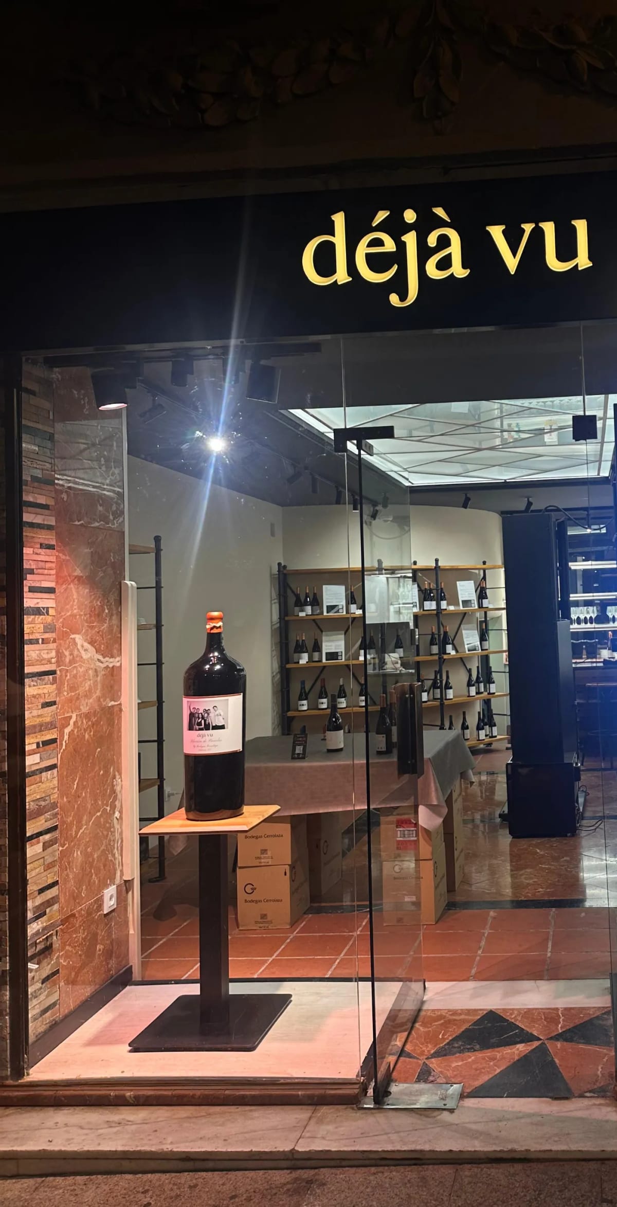 El puesto de Déjà Vu de noche, con el rótulo encendido.